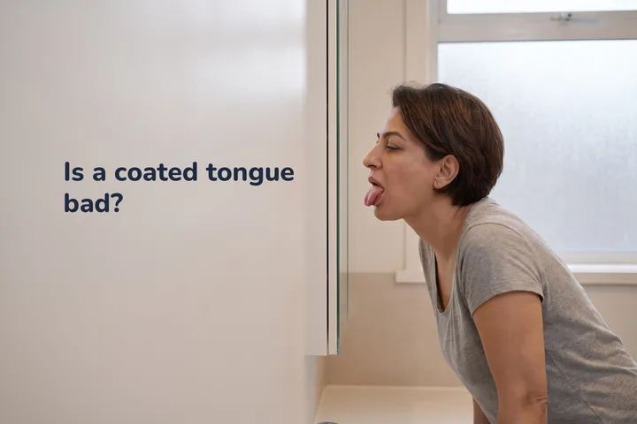 Is a coated tongue bad? — a woman at her bathroom mirror at first light, looking at her own tongue