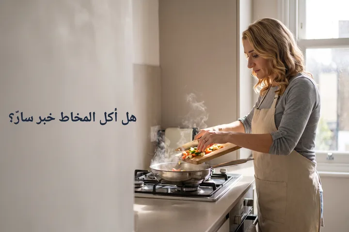 هل أكل المخاط خبر سارّ؟ — امرأة في الأربعين تُفرغ خضارًا مقطّعًا في مقلاة في مطبخها الصباحي