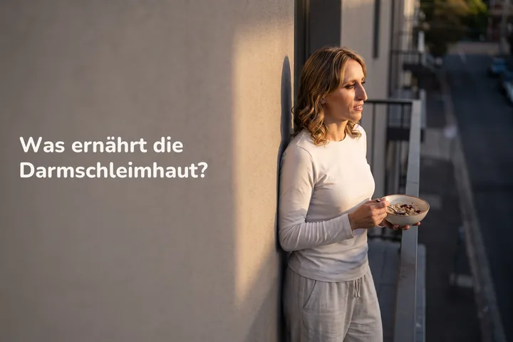 Was ernährt die Darmschleimhaut? — eine junge Frau isst Haferbrei auf ihrem Balkon in der letzten Sonne