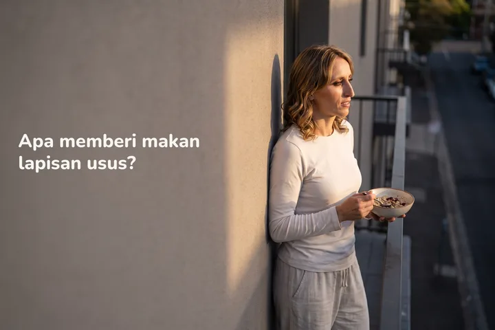 Apa memberi makan lapisan usus? — seorang wanita 20-an makan semangkuk oat di balkoninya dalam cahaya matahari terakhir