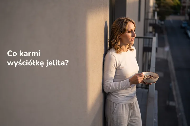 Co karmi wyściółkę jelita? — kobieta po dwudziestce je miskę owsianki na balkonie w ostatnim słońcu