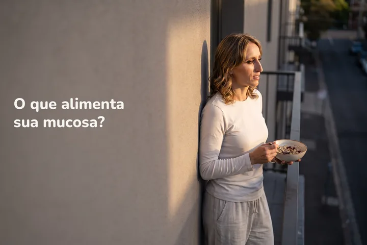 O que alimenta sua mucosa? — uma mulher de uns vinte anos come uma tigela de aveia na varanda, no último sol