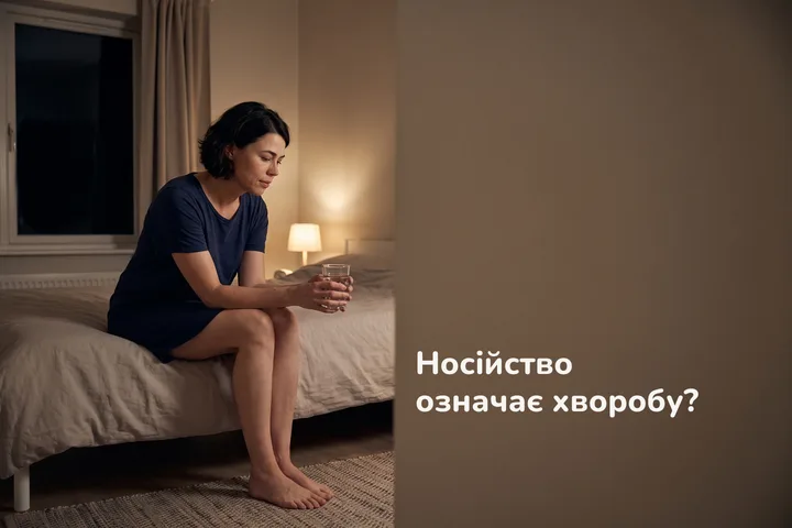 Носійство означає хворобу? — жінка сидить уночі на краю ліжка, тримаючи склянку води обома руками