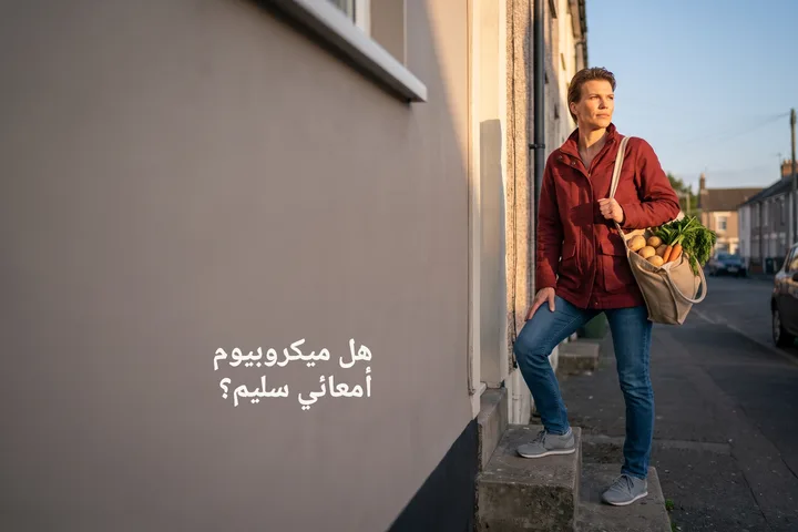 هل ميكروبيوم أمعائي سليم؟ — امرأة تصعد درجات بيتها مساءً وفي يدها كيس خضار