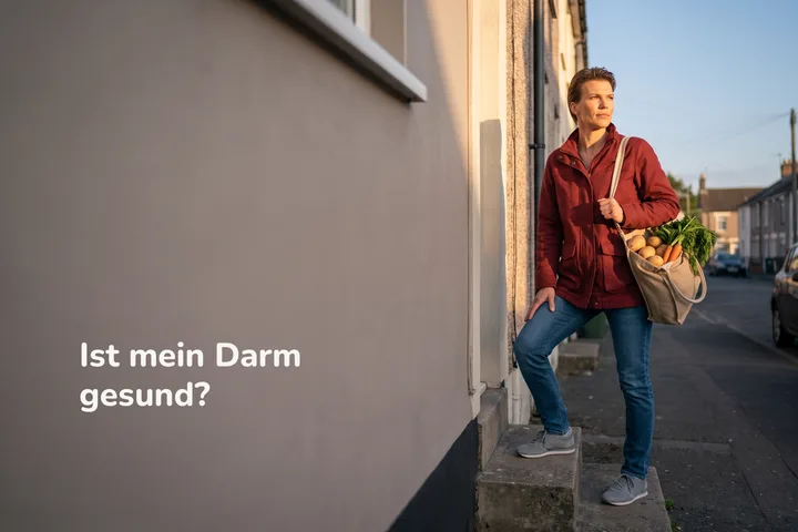 Ist mein Darm gesund? — eine Frau kommt abends mit einer Tüte Gemüse die Stufen zur Haustür herauf