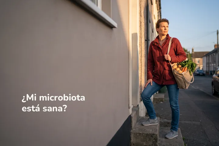 ¿Mi microbiota está sana? — una mujer sube los escalones de su casa al atardecer con una bolsa de verduras