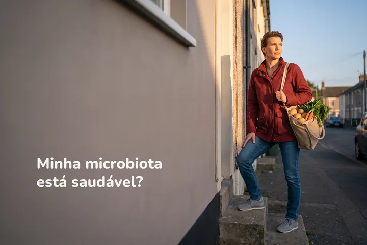 Minha microbiota está saudável? — uma mulher sobe os degraus de casa ao entardecer com uma sacola de verduras