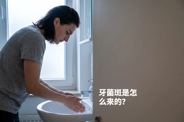 牙菌斑是怎么来的？ — 清晨微凉的光线里，一位女性刚漱完口，俯身在洗手池上