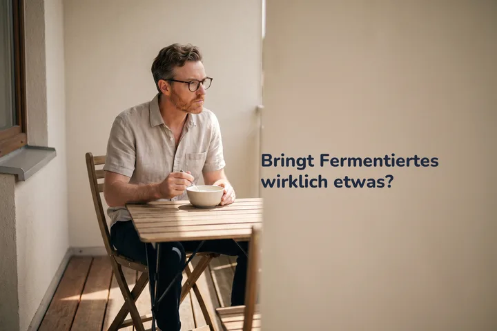 Bringt Fermentiertes wirklich etwas? — ein Mann isst nachmittags Kefir an einem kleinen Tisch auf seinem Balkon