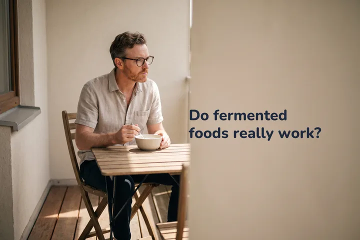 Do fermented foods really work? — a man eats a bowl of kefir at a small table on his balcony in the afternoon